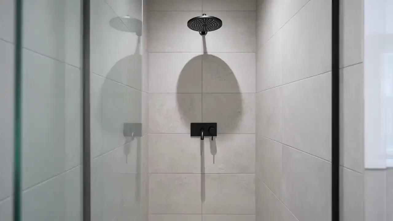 A slow push in on a new matte black shower mixer and rain shower in a renovated bathroom